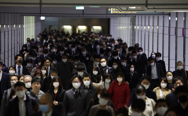 写真・図版 : マスク姿で通勤する人たち＝2020年3月23日、東京都新宿区