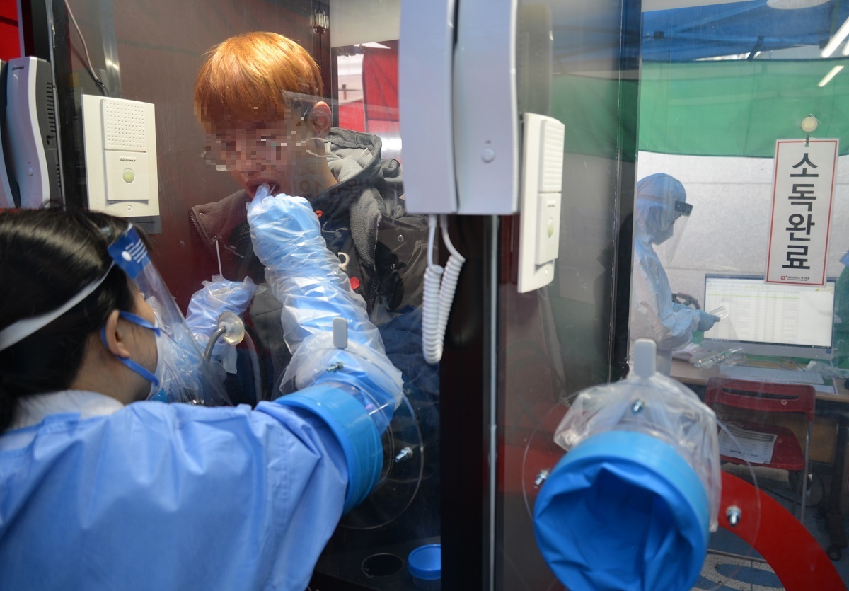 写真・図版 : 韓国でウォークスルー方式PCR検査を受ける男性（画像を一部加工しています） ＝2020年3月20日、ソウル 
