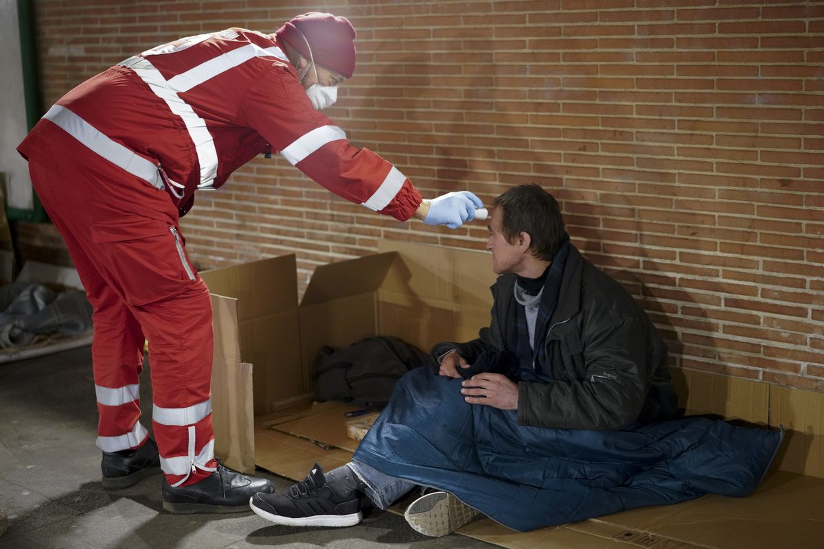 写真・図版 : イタリアのローマでホームレスの男性の検温をする赤十字のボランティア＝AP