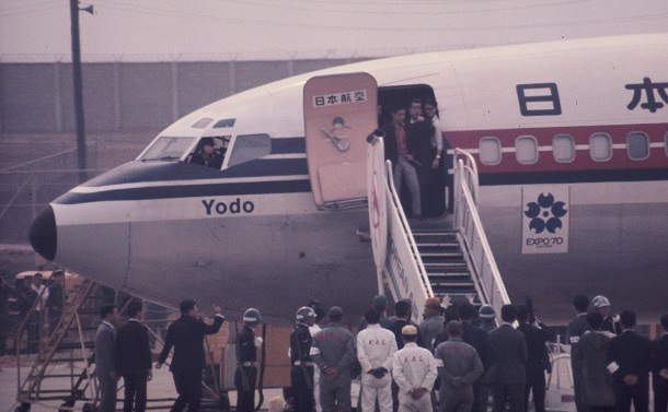 写真・図版 : 韓国・金浦空港でよど号から乗客を降ろすとき姿を見せた赤軍派。赤シャツの男は短刀を手にしている＝1970年4月3日