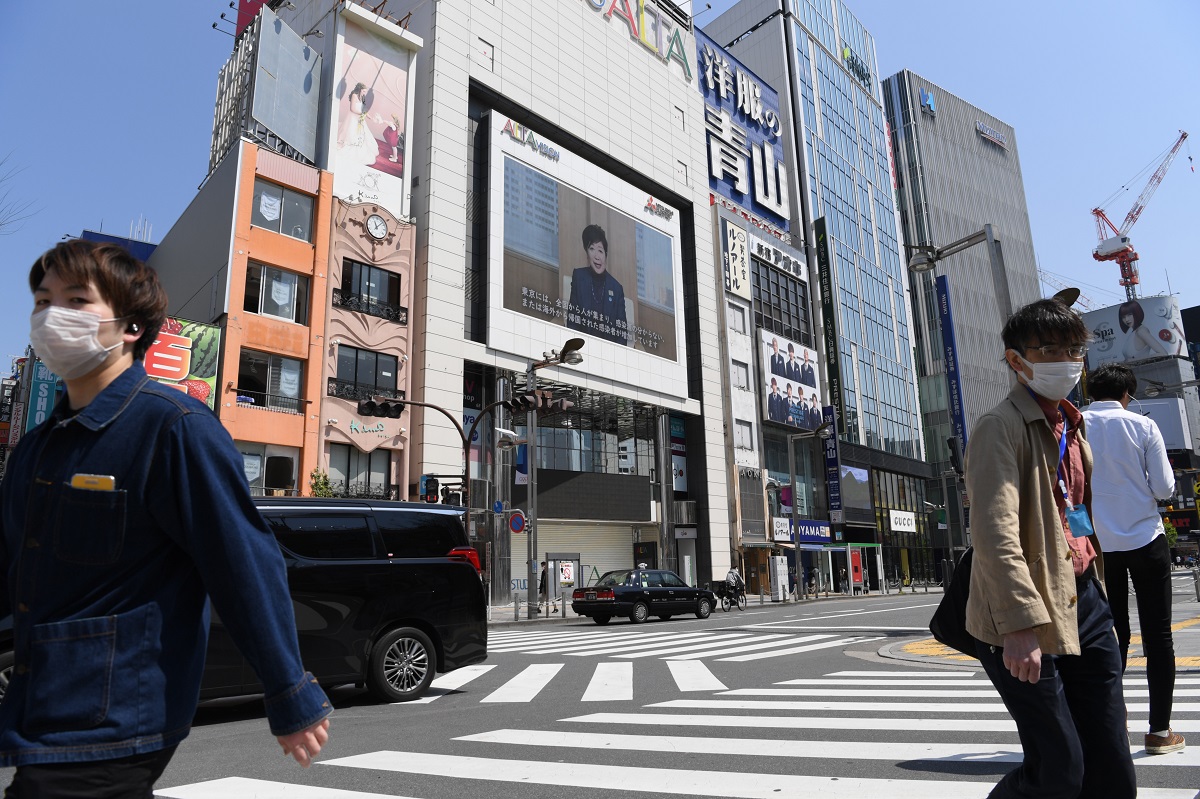 写真・図版 : 外出自粛要請のため新宿駅周辺は人通りが少なく、街頭の大型スクリーンには小池百合子知事が「3密」を避けるように呼びかける映像が流れた＝2020年4月4日、東京都新宿区