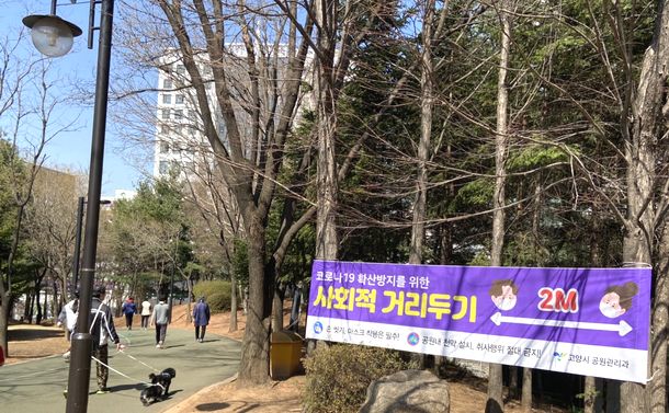 写真・図版 : 公園には「社会的距離置き」を2メートル間隔で実施するのが望ましいという横断幕があちこちに掲げられている＝ソウル市内、筆者撮影