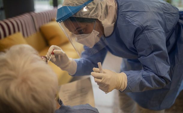 写真・図版 : 2020年4月1日、スペインのNGOのスタッフが、バルセロナにある特別養護老人ホームで高齢女性が新型コロナウイルスに感染しているかを調べる検査のための検体を採取する様子＝AP