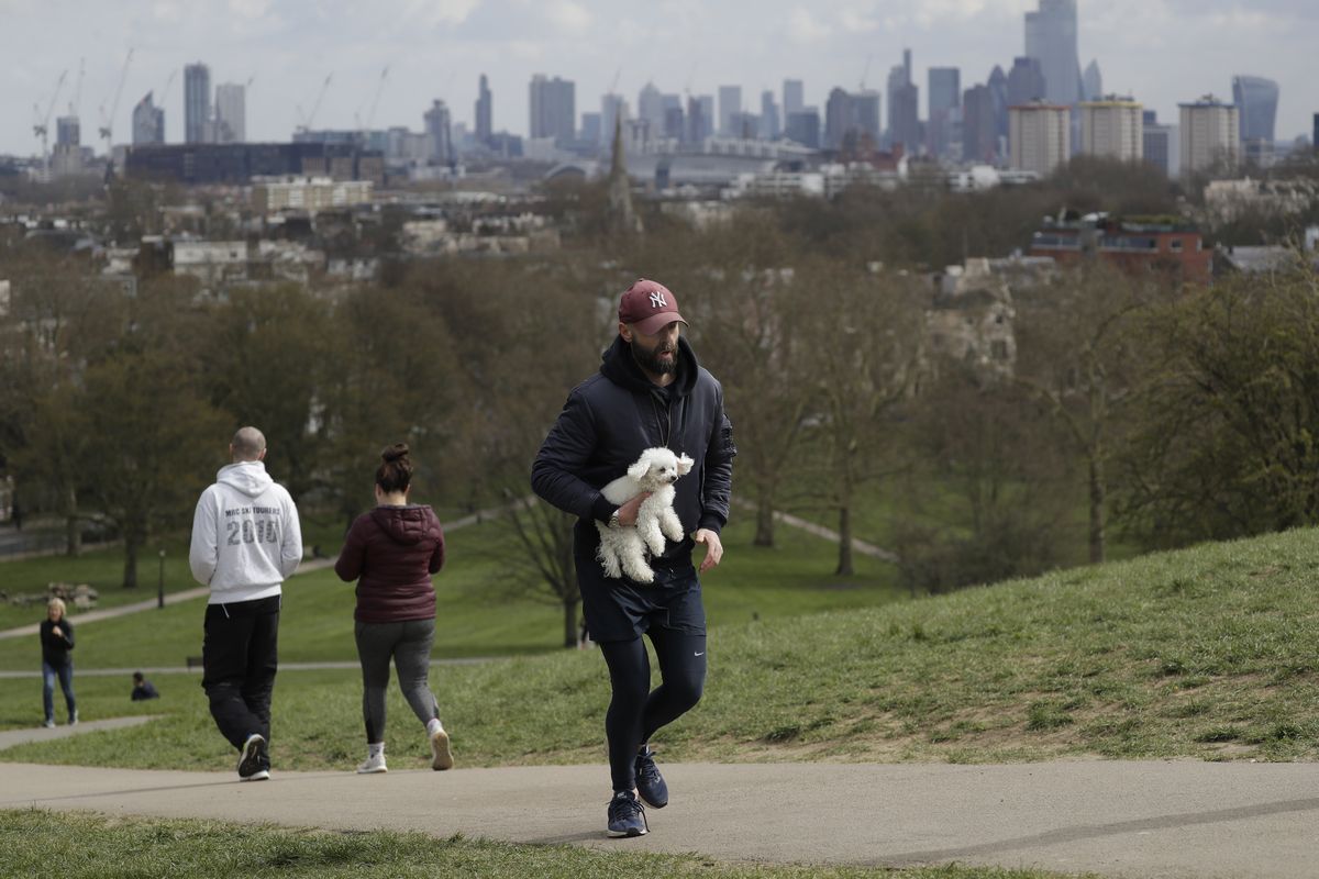 写真・図版 : ロックダウンが続くロンドンで3月31日、公園でジョギングする人たち＝AP