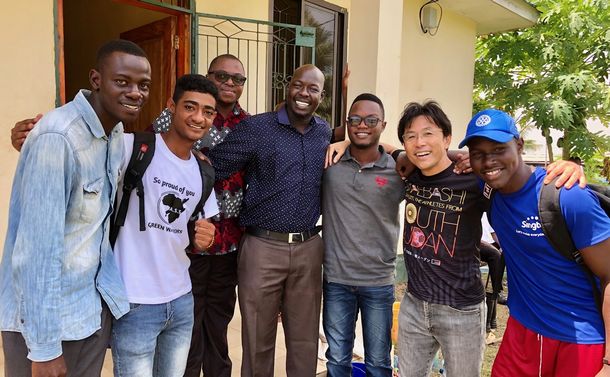 写真・図版 : ピーター(中央)とタンザニア野球関係者。タンザニア野球連盟オフィスの前で、ンチンビ事務局長（左から3人目）らと共に記念撮影。
