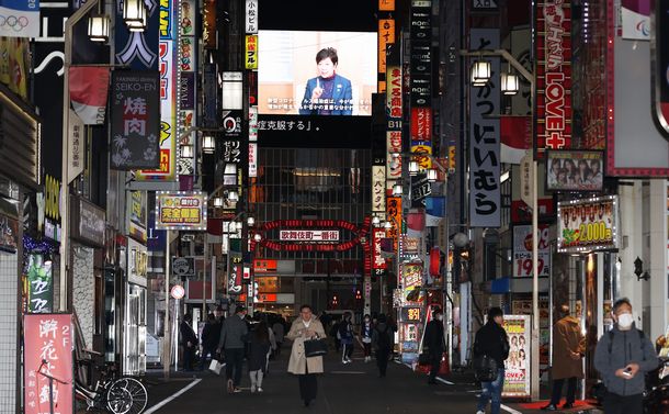 人影がまばらな新宿・歌舞伎町の繁華街。奥の大型ビジョンには、外出自粛などを呼びかける東京都の小池百合子知事が映し出されていた＝2020年4月10日午後7時58分