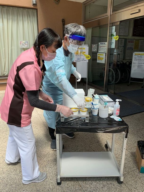 写真・図版 : 病院前でスタッフとドライブスルー型PCR検査の実施に向けて準備する古屋聡さん＝提供写真