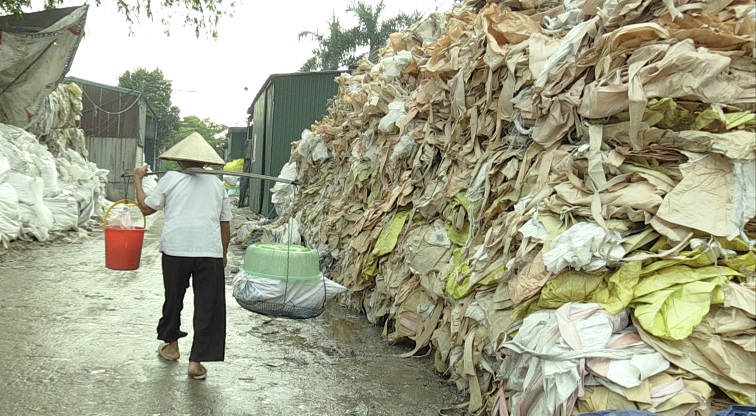 写真・図版 : ベトナム・ミンカイ村のシーン。別名プラスチック村とも呼ばれ、日本を含める先進国から廃棄プラスチックがリサイクル資源として大量に輸入されているが、村のいたるところに処理しきれないプラスチックが散乱している。