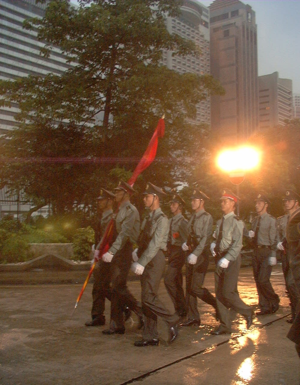 写真・図版 : 香港返還を受けて中国国旗を先頭に駐留英軍総司令部を行進する人民解放軍兵士＝1997年7月1日、香港・金鐘
