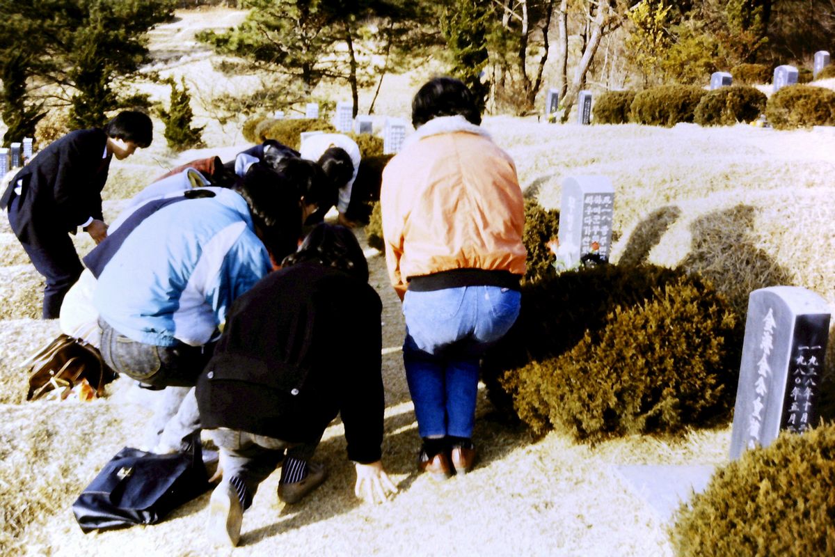 写真・図版 : 軍政時代に民主化運動の弾圧で亡くなった市民の墓前で額ずく人々＝1988年2月、韓国・光州市、筆者撮影