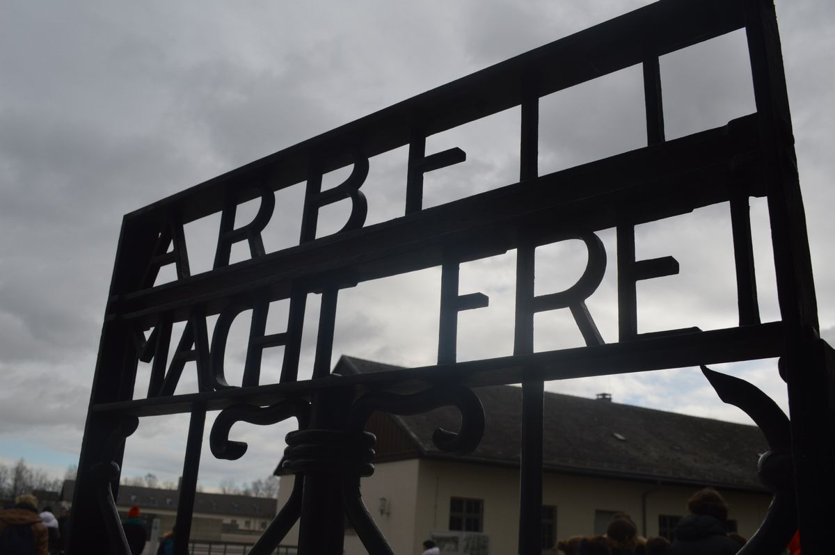 写真・図版 : ドイツ・ダッハウの強制収容所跡の門。”ARBEIT MACHT FREI”（働けば自由に）の文字がはめ込まれている。