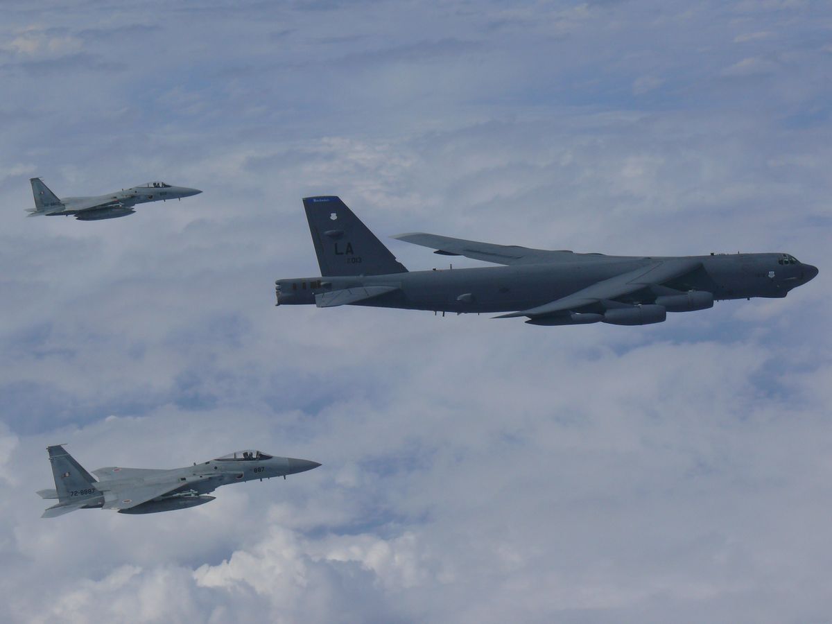 写真・図版 : 東シナ海上空で合同訓練をする米空軍のB52爆撃機と航空自衛隊のF15戦闘機2機=2018年9月。米空軍ホームページより