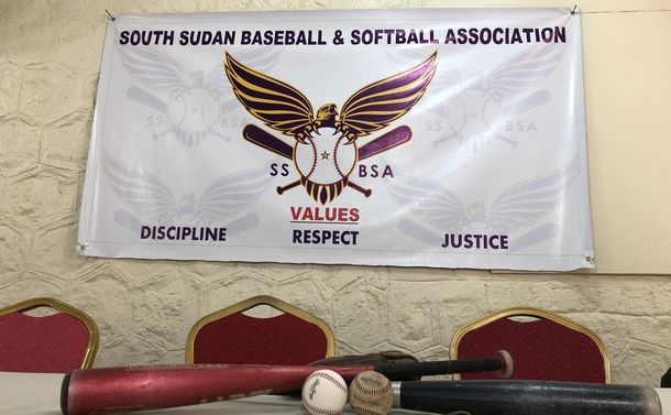 写真・図版 : 野球・ソフトボール連盟のバナー。中央の鷲は南スーダンの国鳥であるサンショクウミワシ。3つの価値がかかれている。
