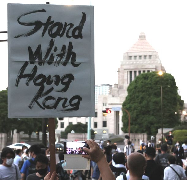 写真・図版 : 国会前でプラカードを掲げ、香港の民主活動家らの逮捕に抗議する人たち＝2020年8月12日、東京・千代田区