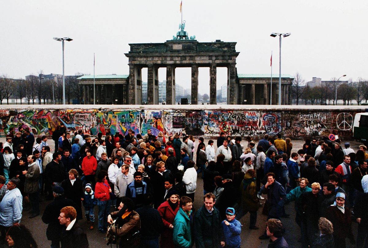 写真・図版 : 1989年11月、東ドイツ政府がベルリンの壁を解放後初めての日曜日に、西側から壁とブランデンブルク門を見ようと集まった東ドイツの人たち=ベルリン。朝日新聞社