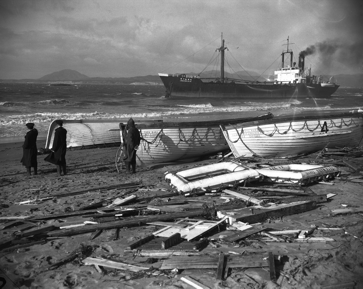 写真・図版 : 「洞爺丸台風」で打ち上げられた救命ボートや船具など。左側の海上に、転覆した洞爺丸の船底が見える＝1954年9月27日、 北海道渡島支庁上磯町七里浜 （現・北斗市）
