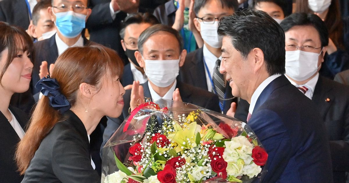 写真・図版 : 首相官邸のスタッフから花束を受け取る安倍晋三首相。中央は菅義偉官房長官（いずれも当時）＝2020年9月16日