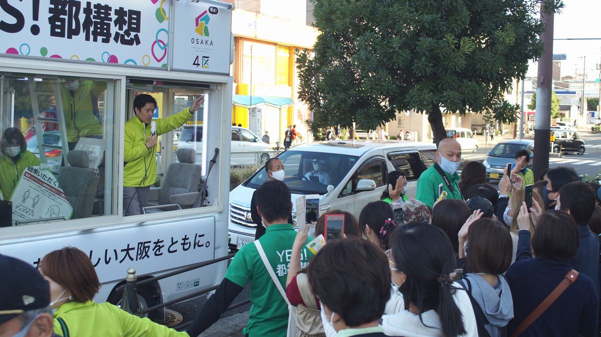 写真・図版 : 投票日前の最後の日曜日、市内街宣に駆け回る吉村府知事。どこでも女性ファンが押し寄せる。大阪市生野区のスーパー前で＝筆者撮影