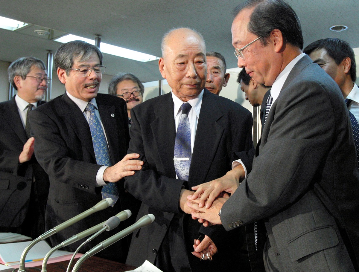 写真・図版 : 和解手続き後、西松建設側の弁護士(右)と握手する中国人元労働者の邵義誠(シャオ・イチェン)さん= 2009年10月23日
