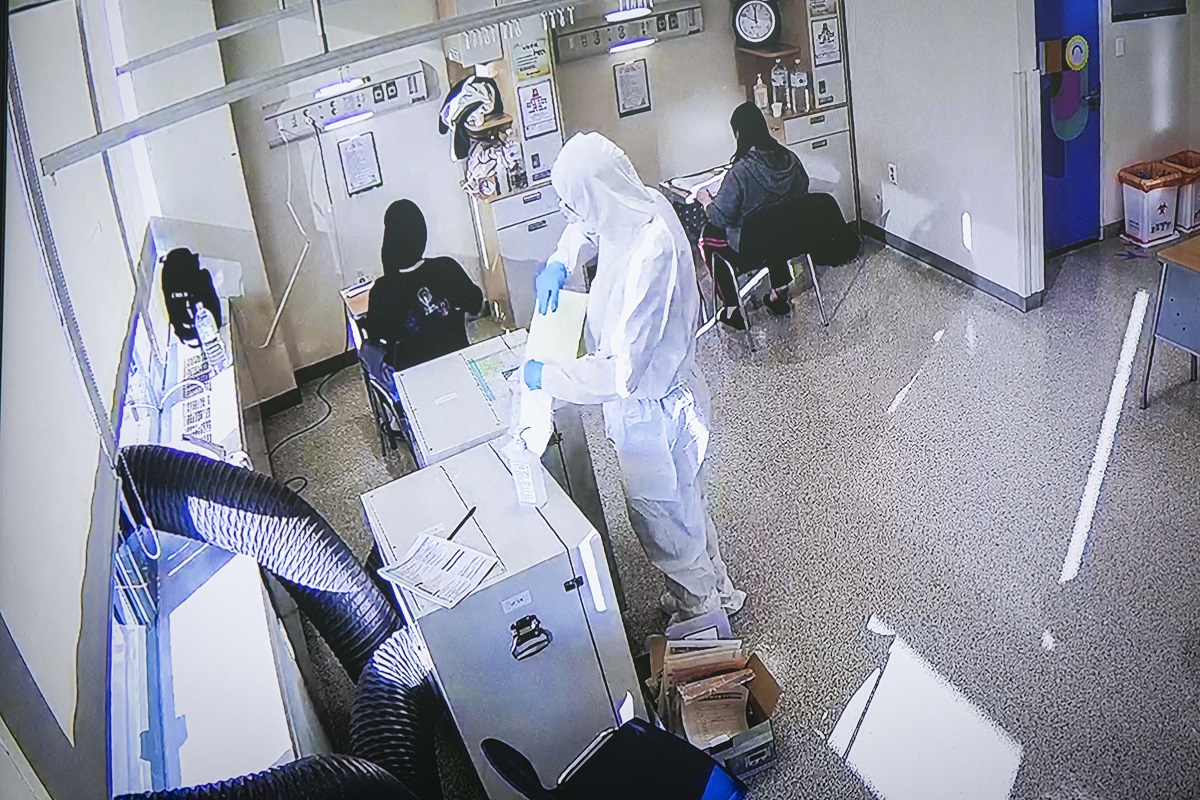ソウル市内の隔離病棟で防護服を着た監督官の下で「大学修学能力試験」に挑む新型コロナウイルスに感染した受験生(上)＝2020年12月3日、東亜日報提供
