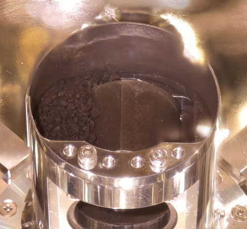 写真・図版 : はやぶさ2のカプセルに入っていた黒い砂（左側）。この分析から新発見が期待される＝宇宙航空研究開発機構（JAXA）提供 
