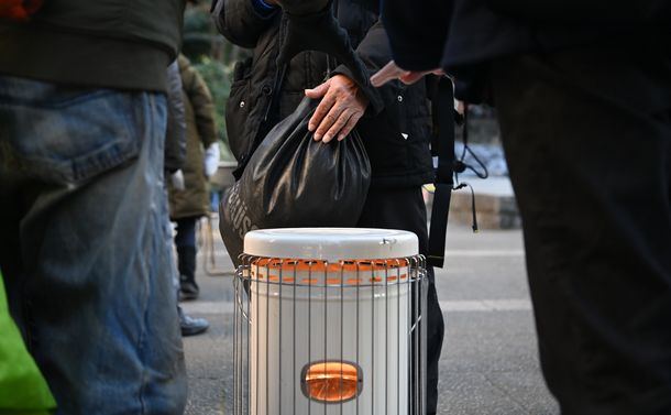 写真・図版 : 市民団体がひらいた困窮者支援の相談会でストーブにあたって食料の配布を待つ人たち＝2020年12月31日午後、東京都豊島区の東池袋中央公園