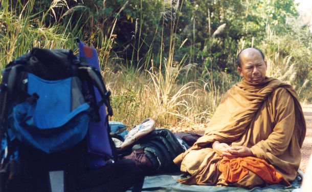 写真・図版 : タイのお坊さんプラチャック氏。手前にあるのは筆者が所持した荷物＝1994年2月、カンボジアとの国境付近で（筆者撮影）