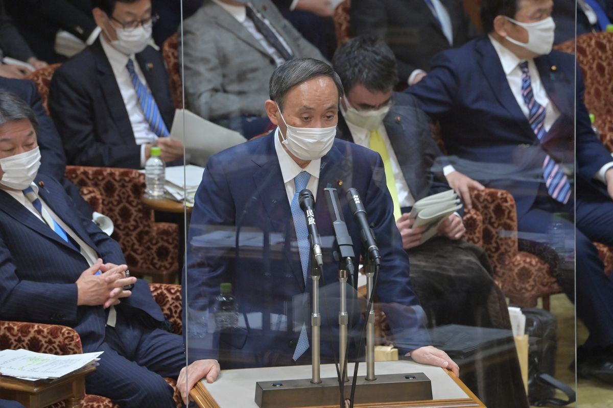 写真・図版 : 1月27日の参院予算委員会で立憲民主党の白氏に答弁する菅首相。右後ろは河野沖縄担当相＝朝日新聞社
