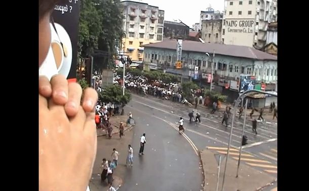 写真・図版 : 2007年9月、ミャンマー最大都市ヤンゴンで日本人ジャーナリスト長井健司さんが銃撃された瞬間。真ん中やや右側で倒れ込む短パン姿の男性が長井さん＝ビルマ民主の声提供