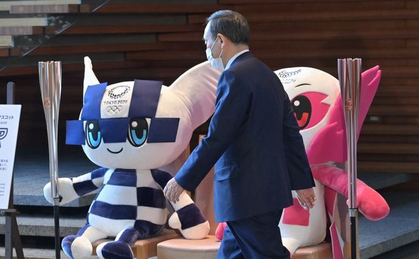 写真・図版 : 首相官邸にある東京五輪とパラリンピックのマスコットの前を歩く菅義偉首相＝2021年2月14日