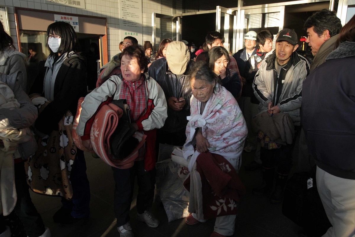 写真・図版 : 避難指示を受け、避難所を出る住民たち＝2011年3月12日、福島県大熊町