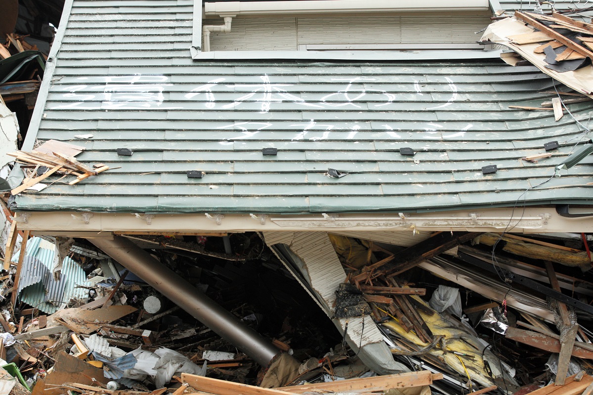 写真・図版 : 倒壊した屋根には「遺体あり」の字が記されていた＝2011年3月19日、宮城県石巻市
