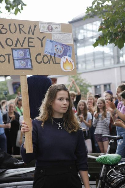 フライデーズ運動のデモで、「石炭ではなく、金を燃やせ」というプラカードを掲げる女性＝2019年8月、ドイツ・ベルリン、筆者撮影