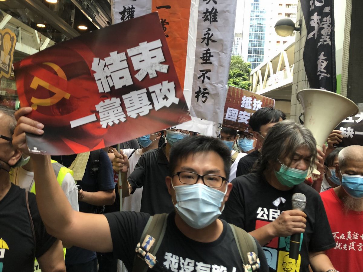 写真・図版 : 香港国家安全維持法の施行に反対する香港のデモ行進。「（中国共産党の）一党独裁を終わらせよ」と書かれたビラを掲げる参加者も＝2020年7月1日、香港