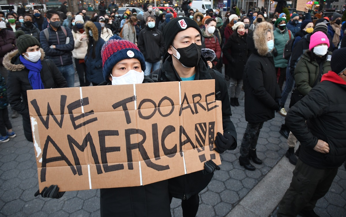 米ジョージア州で起きた銃撃事件の犠牲者を悼むニューヨークの集会で２０２１年３月１９日、「私たちも米国だ」と書かれたボードを掲げるアジア系市民20210320
