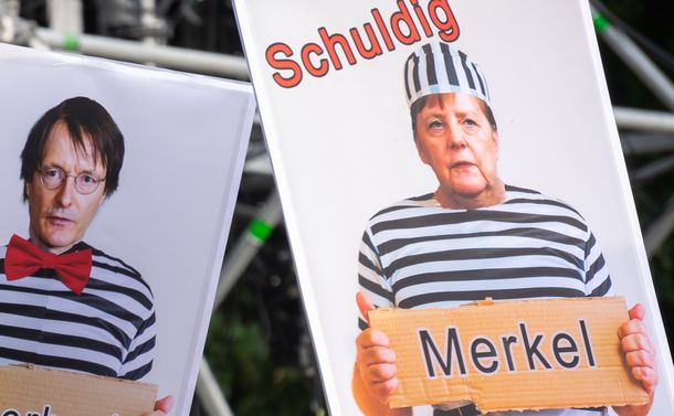 写真・図版 : 政府のコロナ対策に抗議するベルリンでのデモでは、メルケル首相らを囚人に模して「有罪」と記したボードが掲げられていた＝Jaz_Online/Shutterstock.com