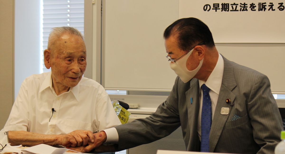 写真・図版 : 自民党の河村建夫衆院議員（右）と握手する李鶴来さん＝2020年6月15日、東京・永田町の衆院第2議員会館