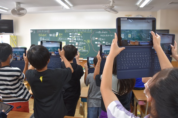 写真・図版 : 授業後、黒板の板書をタブレット端末で撮影して保存する児童たち＝2020年10月、愛知県の小学校