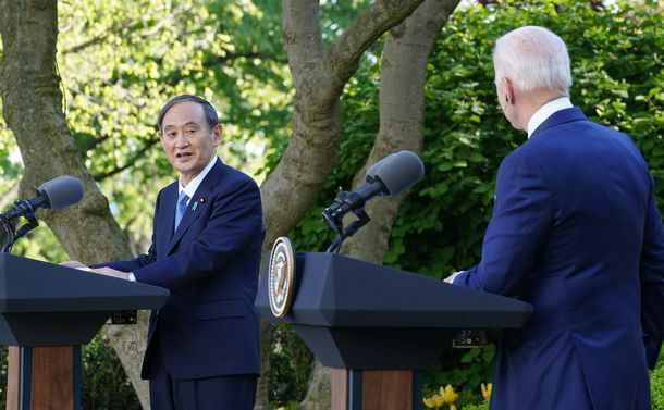 写真・図版 : 日米首脳会談後に共同会見で発言する菅義偉首相。右はバイデン大統領＝2021年4月16日、ワシントンのホワイトハウス