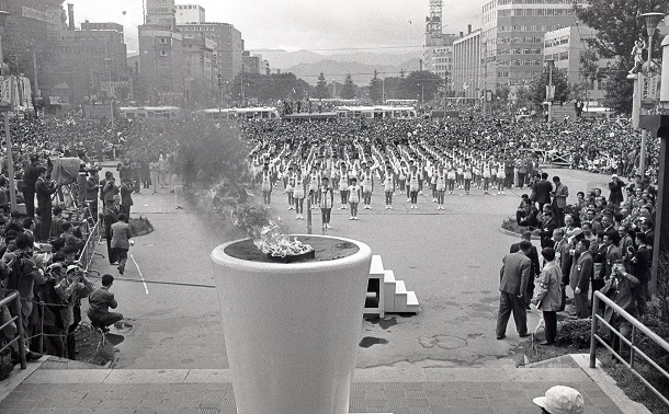 写真・図版 : 札幌テレビ塔下の聖火台に点火された1964年東京五輪の聖火。後方は大通公園=1964年9月10日、札幌市