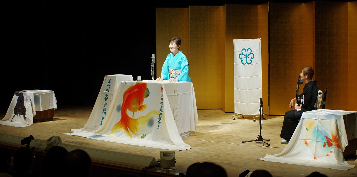 写真・図版 : 筆者が演じる浪曲の舞台。テーブル掛けが五つの台を飾る。この時「盆栽」はなかったけれど、十分、派手！＝御堂義乗撮影