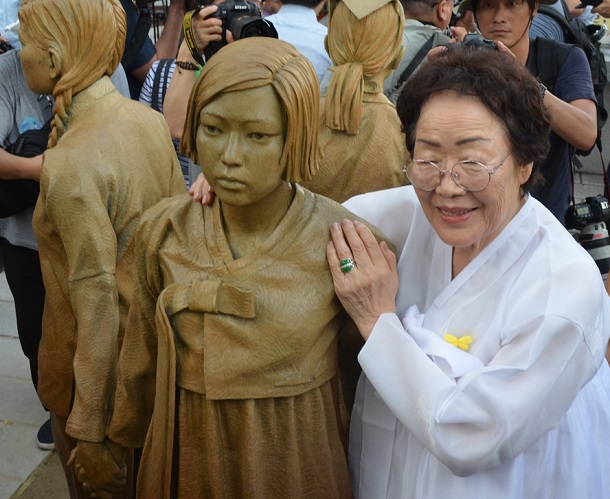写真・図版 : ソウル市が新たに設置した少女像に寄り添う元慰安婦の李容洙さん＝2019年8月