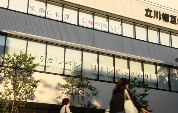 写真・図版 : 病院の窓に貼られた「医療は限界」「五輪やめて！」などと書かれた紙＝2021年5月6日、東京都立川市