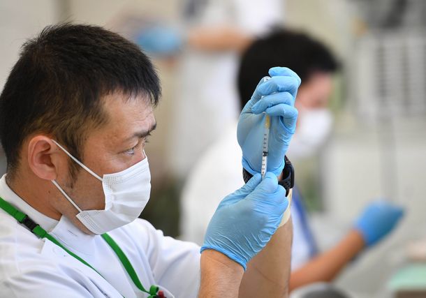 写真・図版 : 新型コロナウイルスワクチンをバイアル（容器）から注射器で吸い出す自衛隊の准看護師＝2021年5月24日、東京・大手町、代表撮影