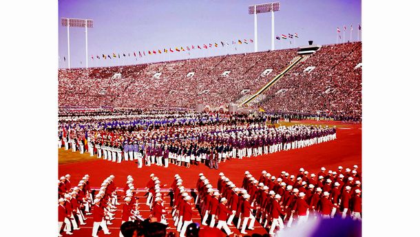 写真・図版 : アジア最初のオリンピックが1964年10月10日開幕し、東京・国立競技場で開会式が行われた。秋空の下、天皇陛下が開会を宣言し、94カ国の選手団が7万5千人の観衆の拍手を受けて入場行進した。15日間、5500人余の選手が技を競った。写真は、最後に入場行進する日本選手団