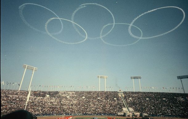 写真・図版 : 東京五輪開会式では、東京上空に航空自衛隊のジェット機（ブルーインパルス）が五色の大輪を描いた＝1964年10月10日