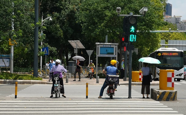 写真・図版 : 深圳の横断歩道には監視カメラが備えられ、ディスプレイには顔認識で違反者の顔をさらすという警告が出ていた=2018年5月