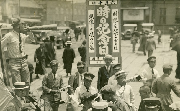 写真・図版 : 生活改善運動として行われた時の記念日の啓発キャンペーン。「時限を誤らざるは　規律を保つの始」と書かれている＝1929年6月10日、大阪・難波駅前 

