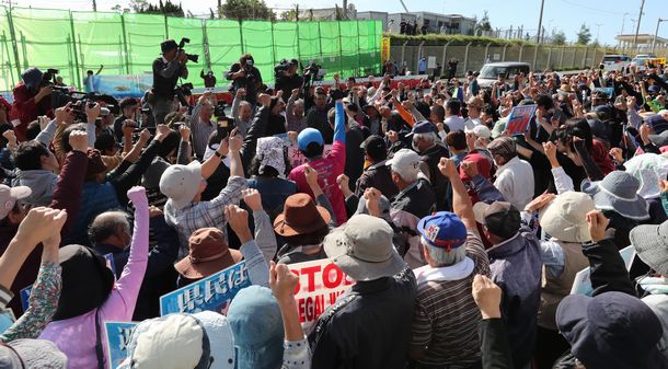 写真・図版 : 沖縄県名護市辺野古の沿岸に土砂投入が始まった翌日、米軍キャンプ・シュワブのゲート前で抗議集会が開かれた。玉城デニー知事（後方中央）も駆けつけた＝2018年12月15日、名護市