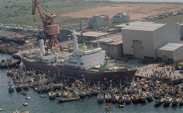 写真・図版 : 出港に反対する漁民たちの漁船に取り囲まれた原子力船「むつ」。朝日新聞社ヘリコプターから＝1974年8月25日